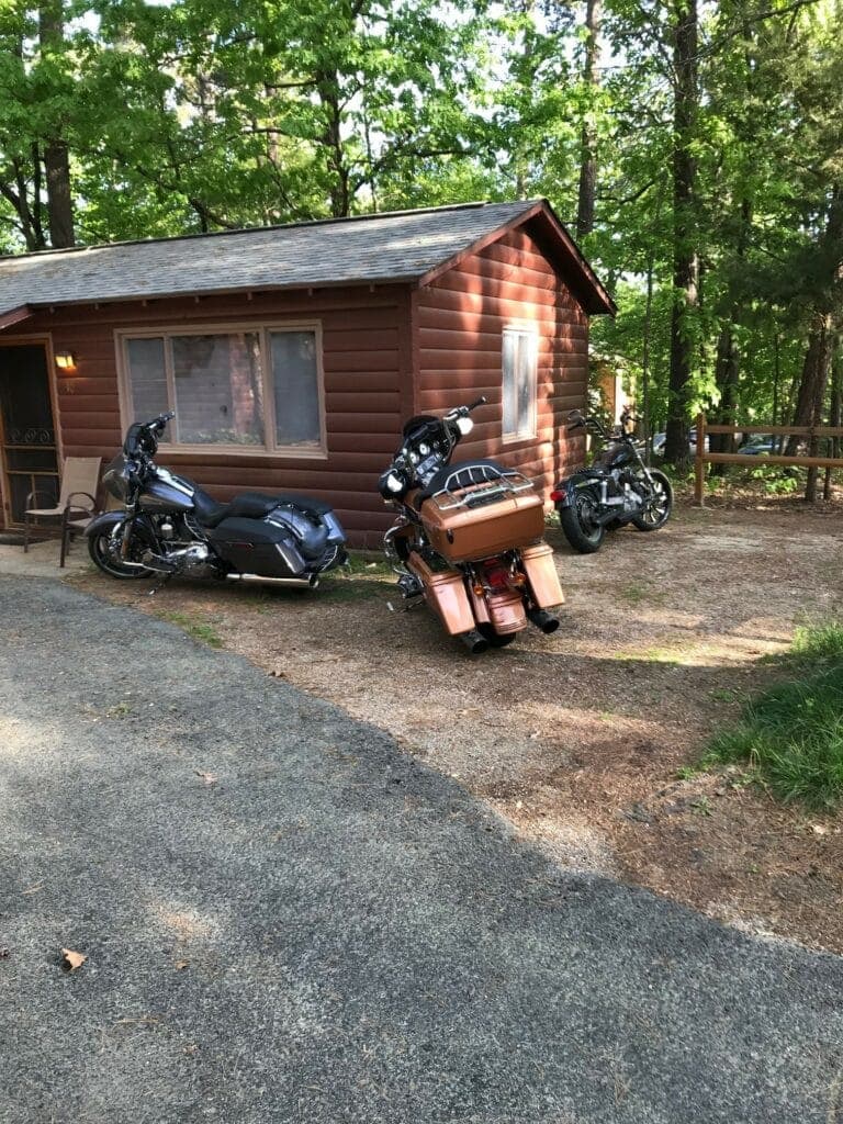 A log cabin with three motorcycles parked in front.