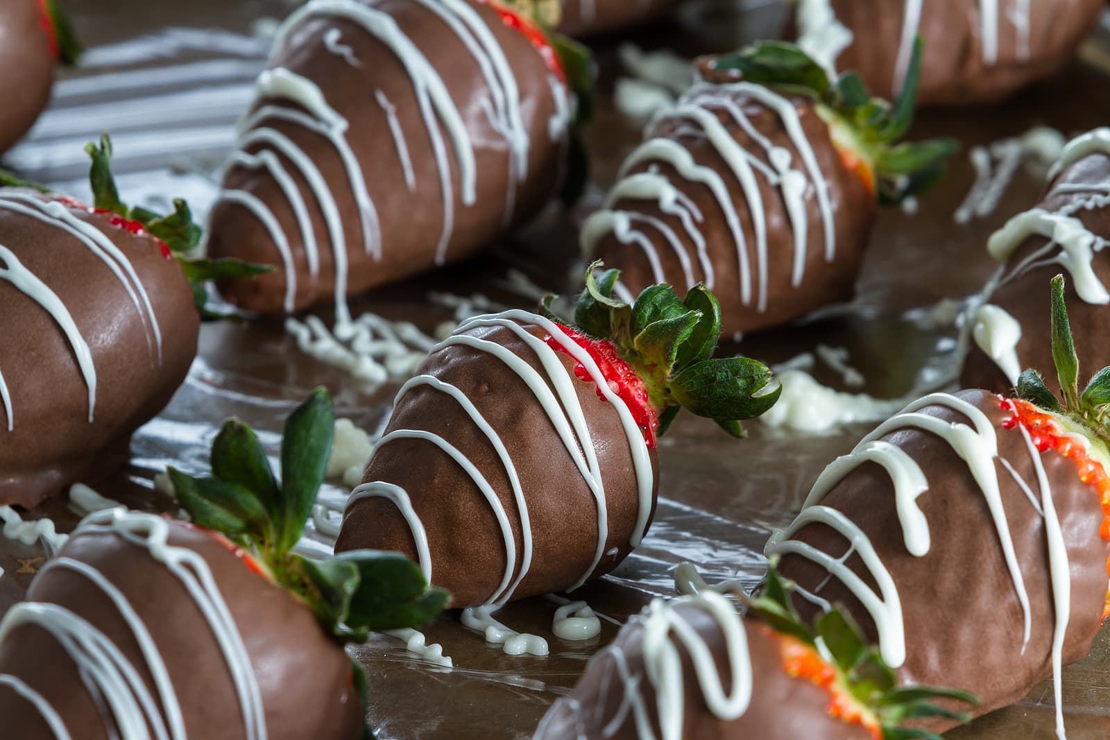 A close-up of chocolate-covered strawberries drizzled with white chocolate.