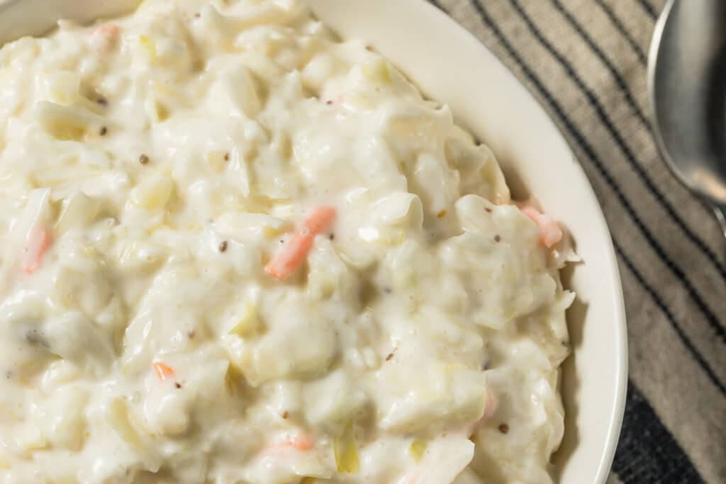 A creamy bowl of coleslaw with visible vegetables and a smooth dressing.