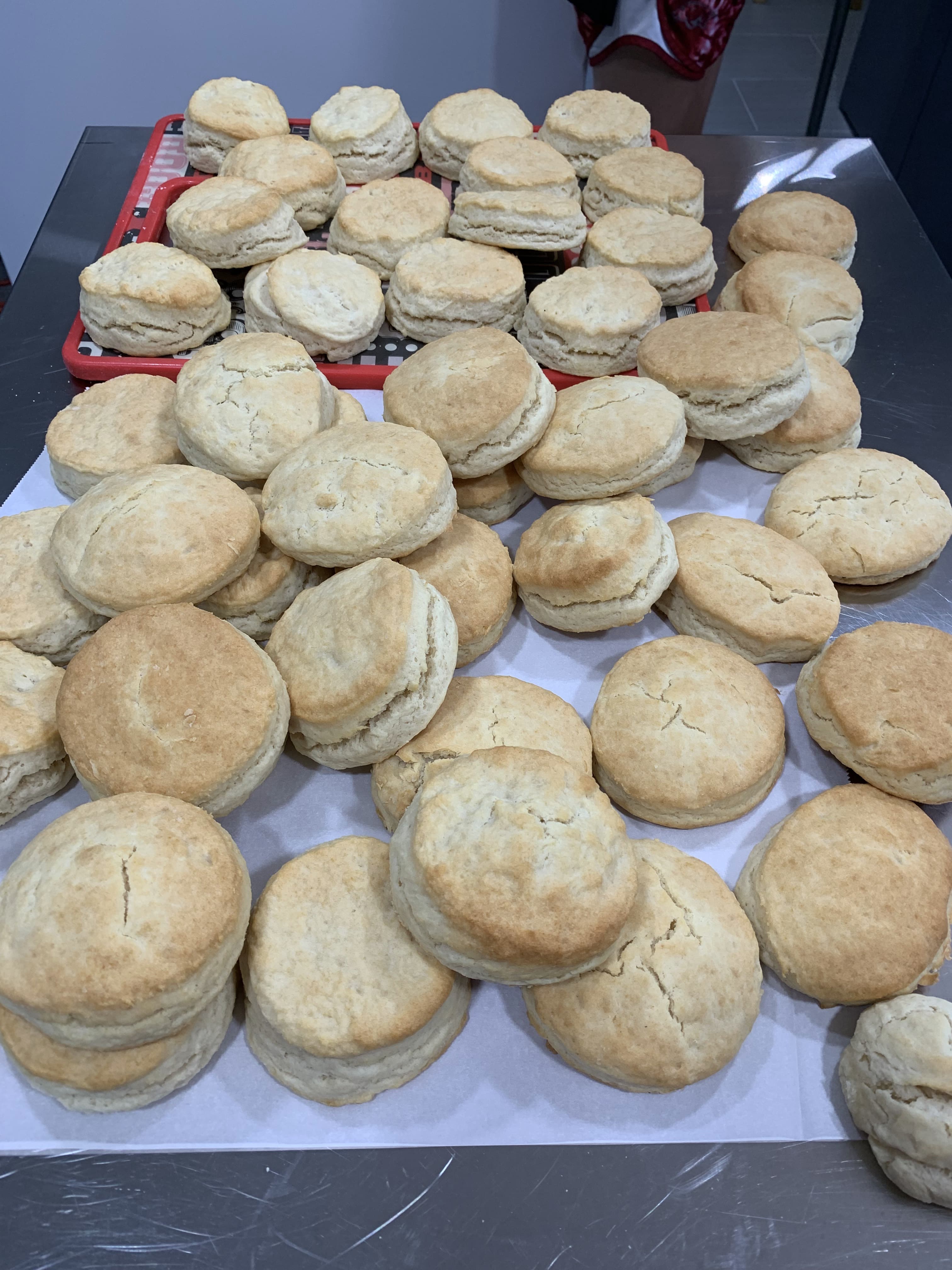 A large pile of freshly baked, golden-brown biscuits on a tray.