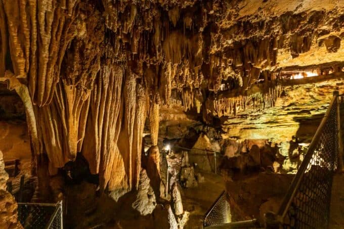 Cave with formations hanging from the ceiling lighted in a yellow glow