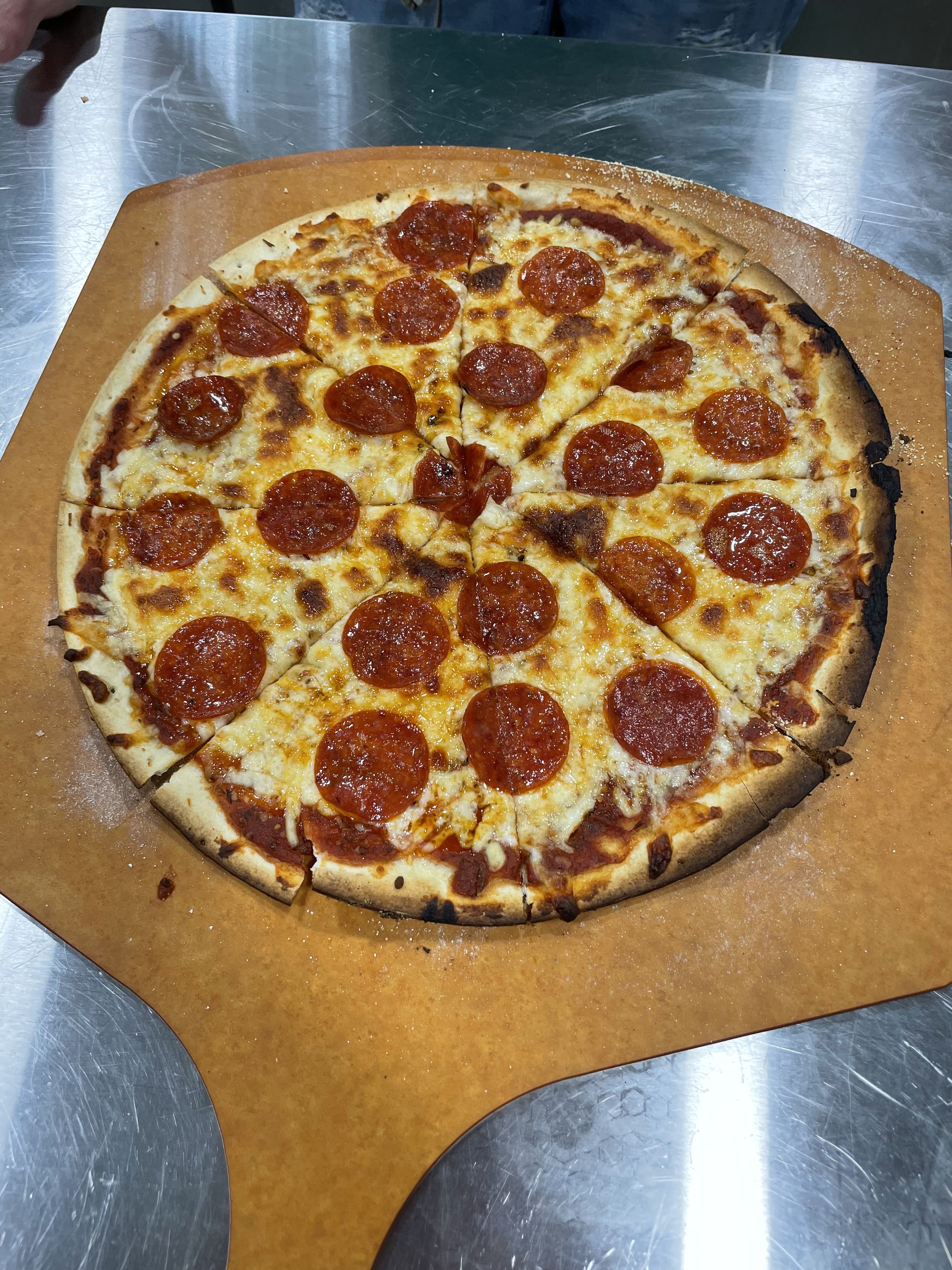 A freshly baked pepperoni pizza on a wooden serving board.