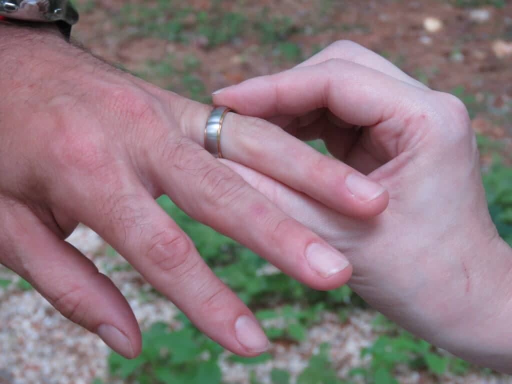 A close-up of two hands, one with a wedding ring, gently touching each other.