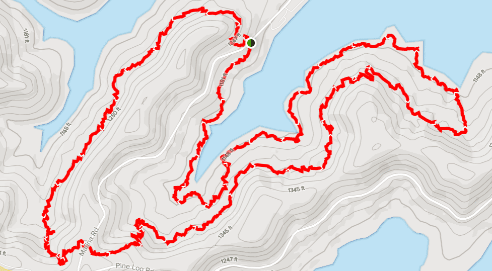 A topographic map showing a winding hiking trail marked in red overlaid on a blue lake background.