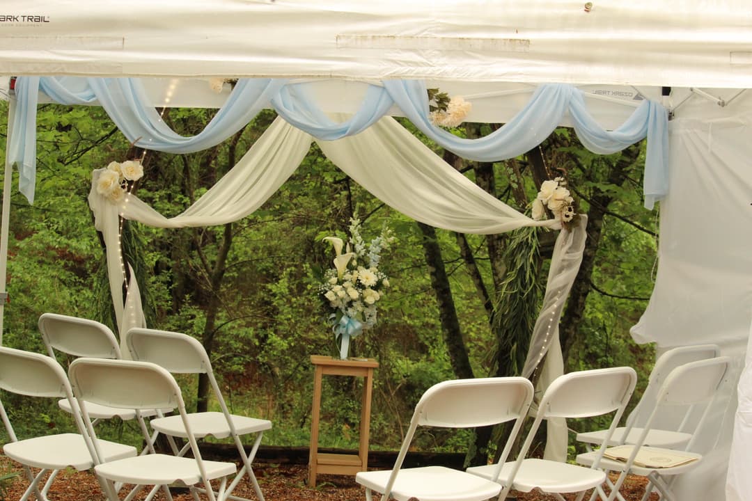 Large bouquet of flowers on a small table surrounded by white and blue drapping