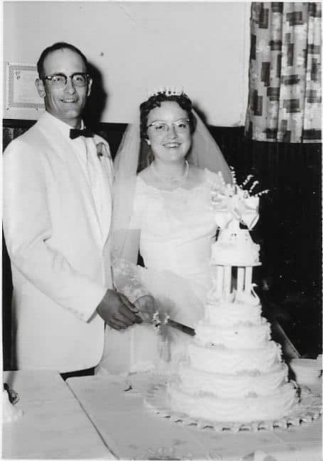 man and woman standing at a wedding cake dressed for a wedding