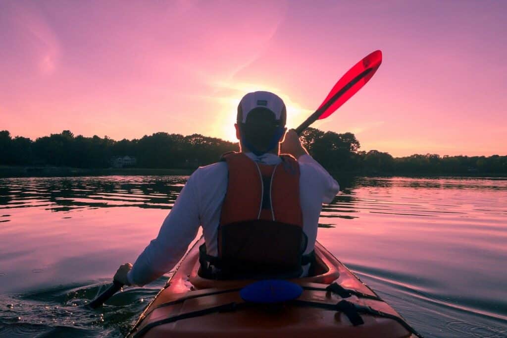 man kayaking into the sunset