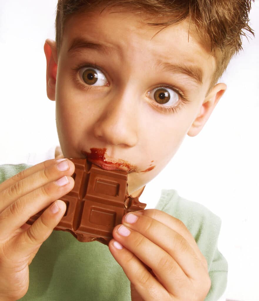 Boy enjoying eating chocolate bar with chocolate all over face