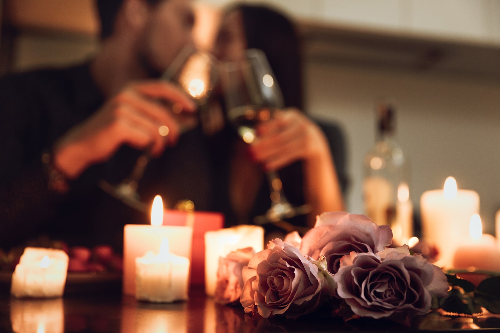 a couple having dinner by candle light toasting with glasses of red wine