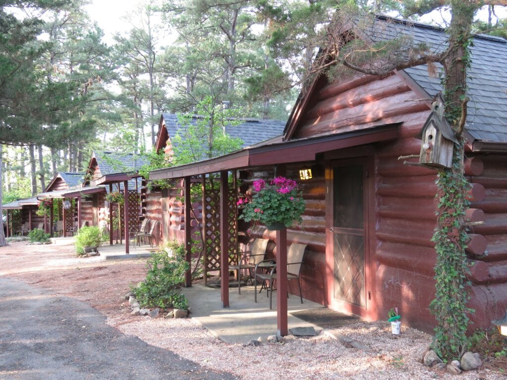 historic cabin situated all in row with plants hanging by the doors 