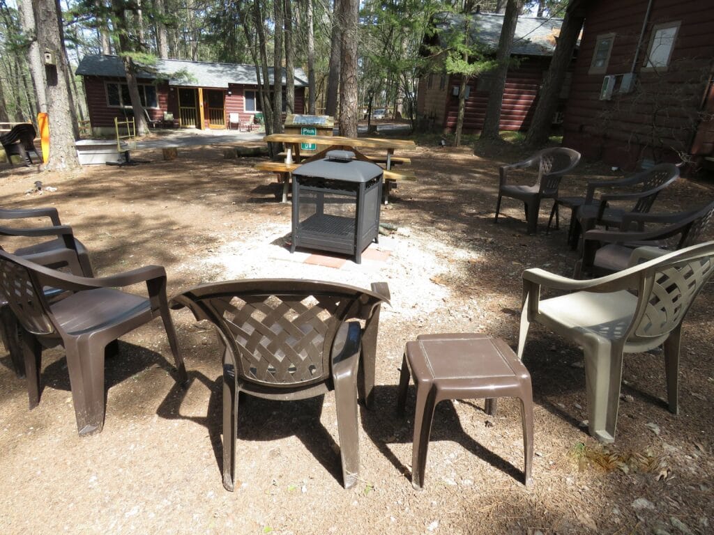 Property of cabins showing a gathering space with chairs and a firepit.