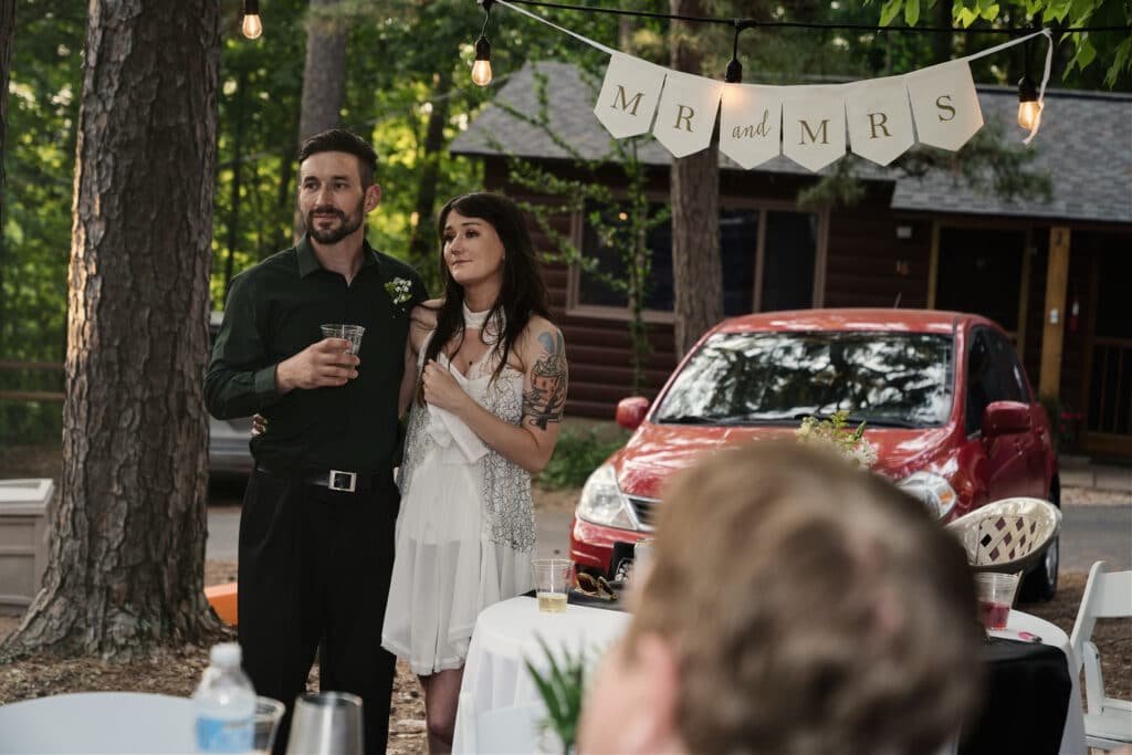 bride and groom making a toast with cabins in the background