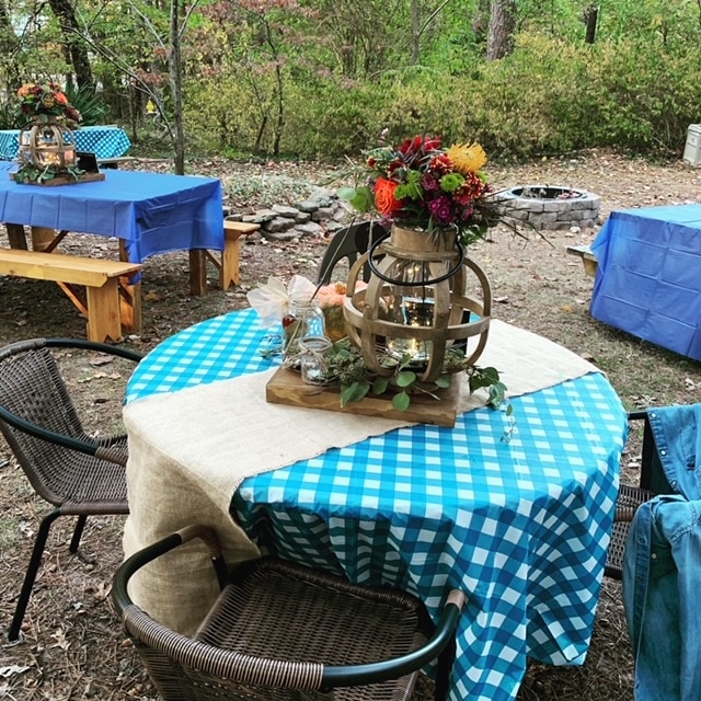 Round tables with blue checked cloths and fall centerpieces shaped like pumpkins for a rustic wedding
