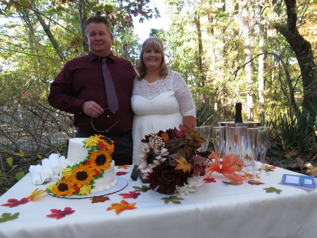 bride and groom standing at the bridal table with a wedding cake and toasting champagne