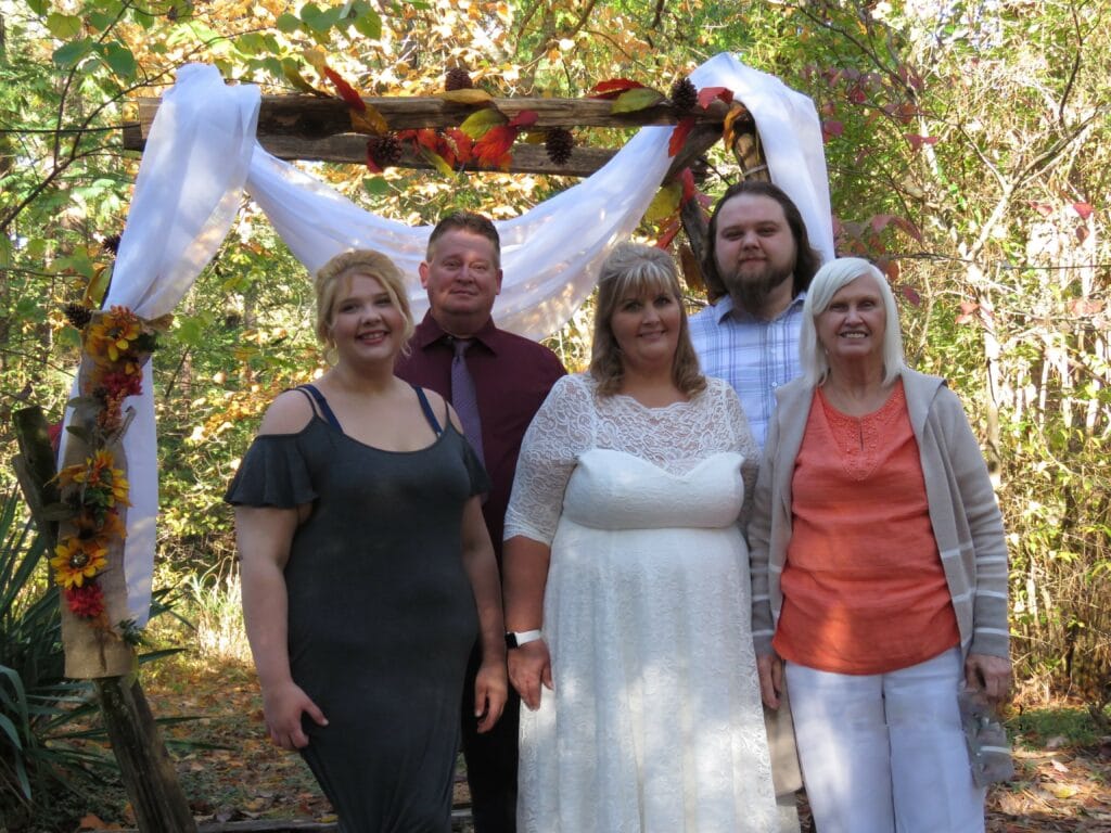 bride and family at outdoor wedding in front of rustic arch