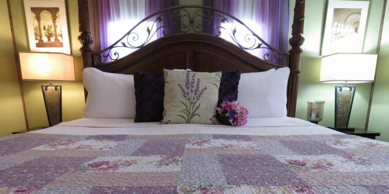 Bed with purple bedspread and lamps on nightstands