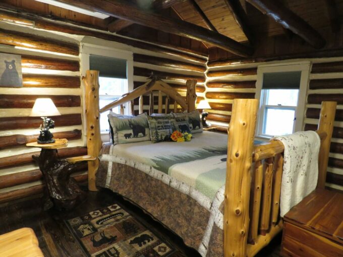 Log cabin with king sized log bed with black bear quilt and black bear lamps on tree hardwood night stands