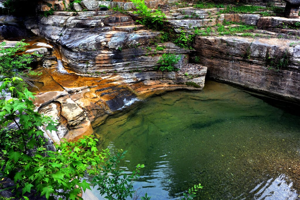 Pool of water surrounded by limestone bluffs and vegetation 