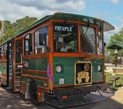 Green wood sided Trolley picking up passenger on a city street and one of the best ways to explore eureka springs